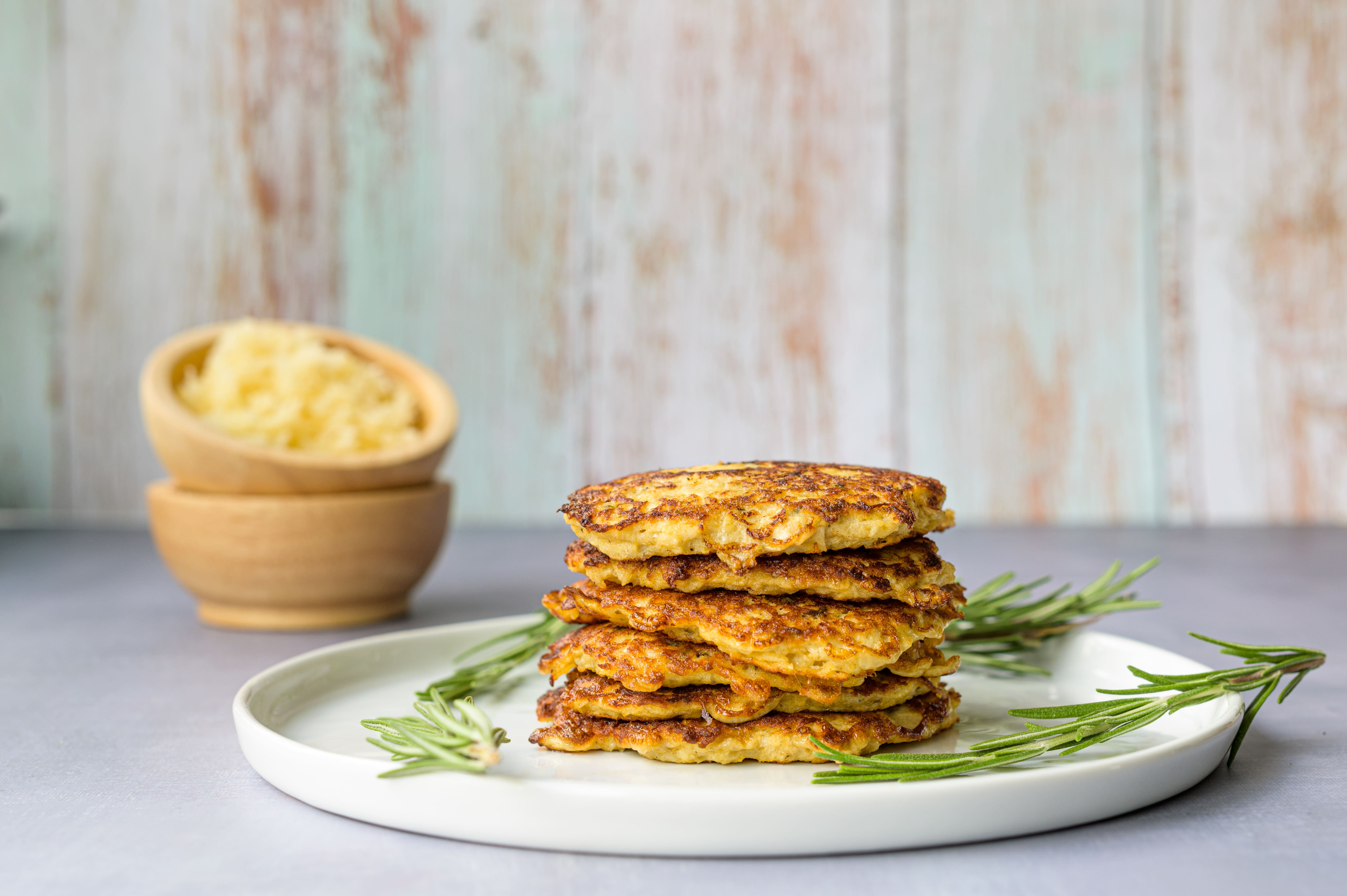 Krokante rösti van koolraap op een wit bord met herfstbladeren op de achtergrond — koolhydraatarm keto bijgerecht