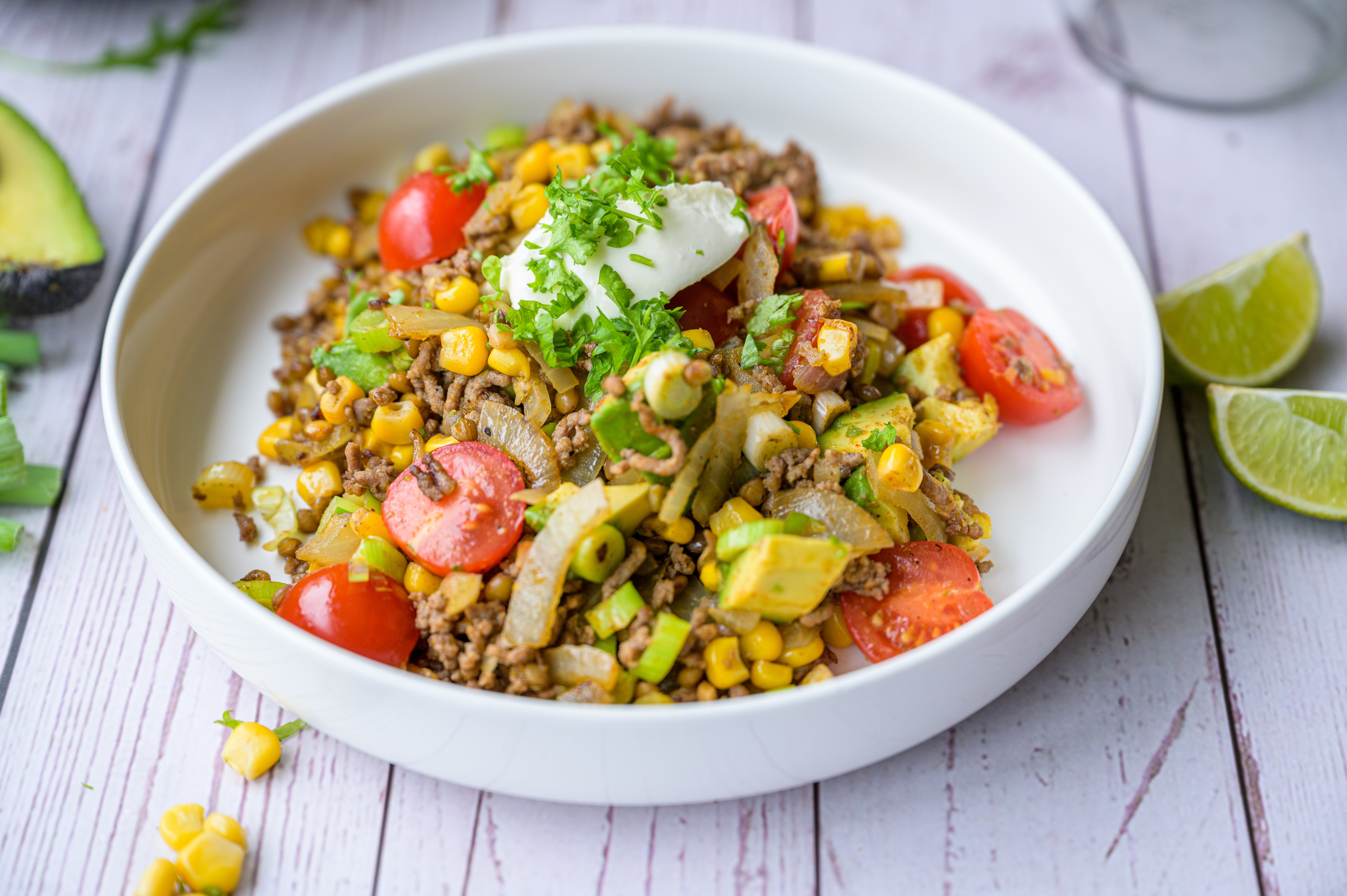 Mexicaans eenpansgerecht met rundergehakt, linzen, avocado en cherrytomaatjes in een witte kom — koolhydraatarm dinerrecept