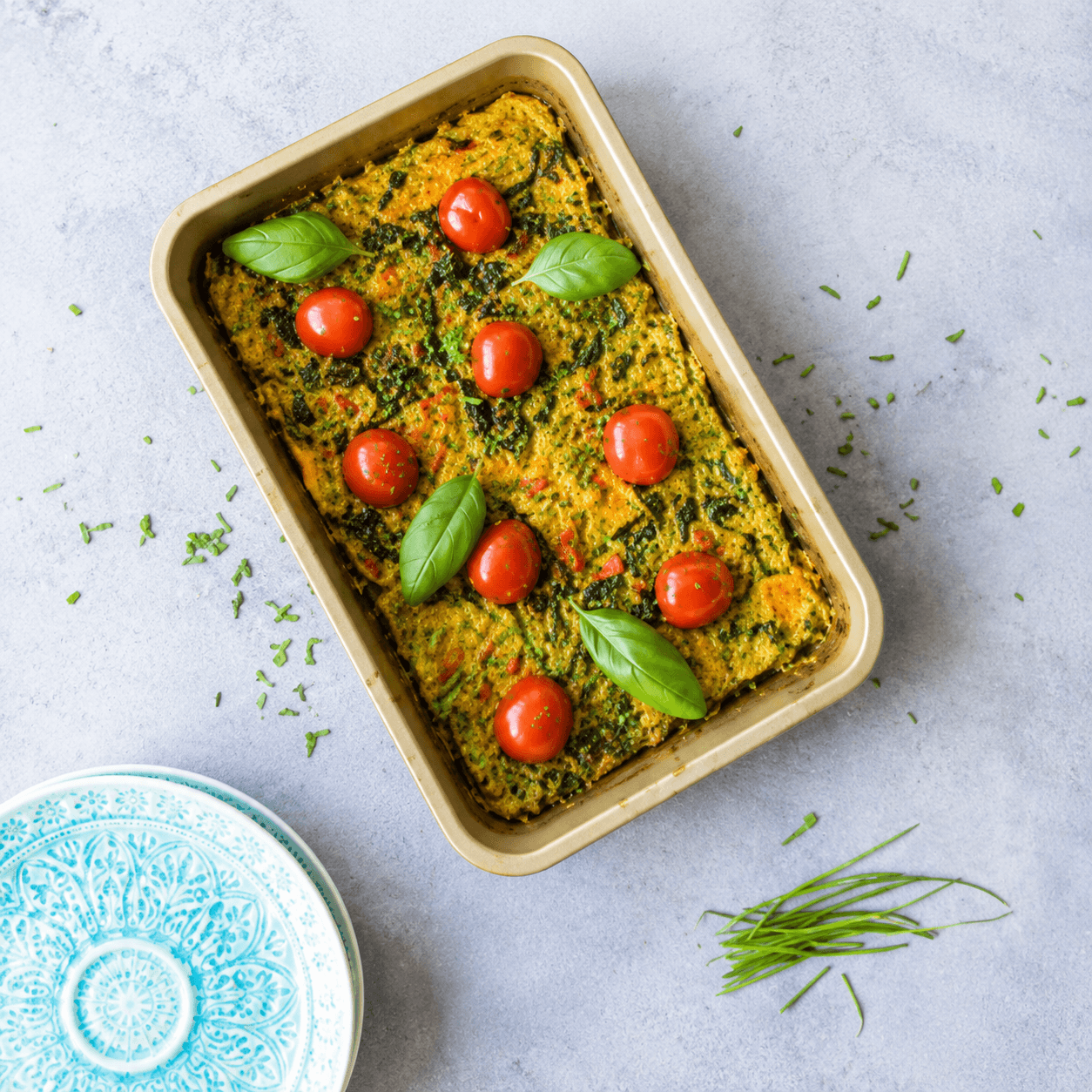 Vegan frittata met spinazie, rode paprika, cherrytomaatjes en bieslook in een ovenschaal — koolhydraatarm plantaardig dinerrecept