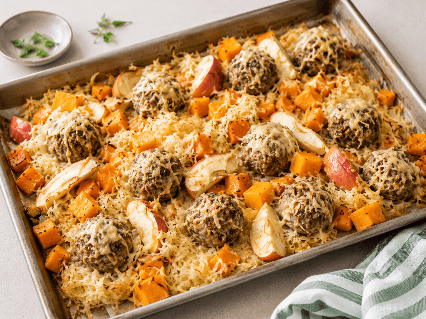 Zuurkool traybake met gehaktballetjes, pompoenblokjes, appelpartjes en gesmolten kaas op een bakplaat — koolhydraatarm herfstrecept voor 4 porties