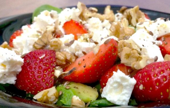 Koolhydraatarme salade met aardbeien, avocado, feta en walnoten op een bed van spinazie