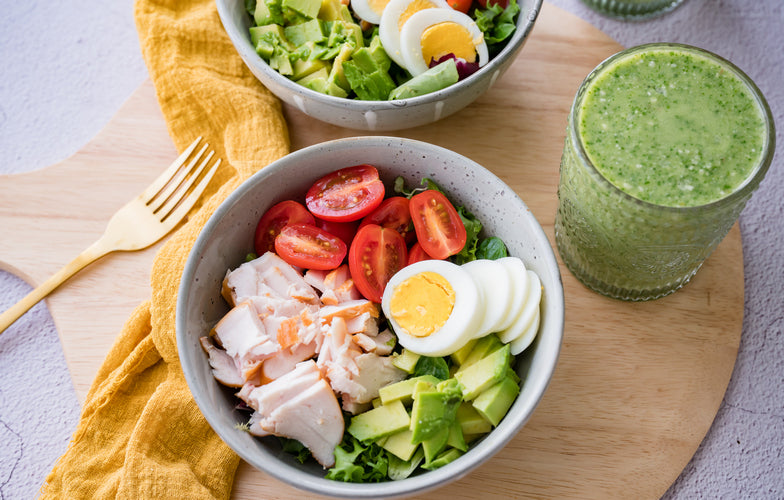 Koolhydraatarme Buddha Bowl met kip, avocado, ei, 
tomaat en spinazie in een grijze kom — gezonde 
maaltijd van Makkelijk Afvallen