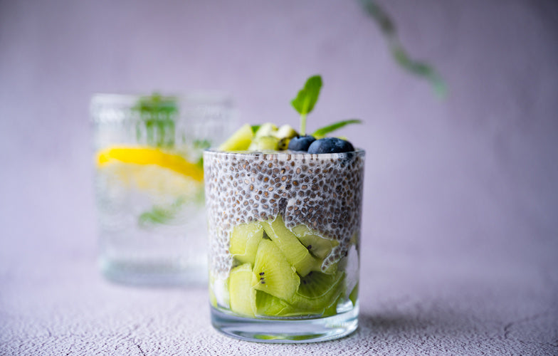 Chiapudding met kiwi in een glas, gegarneerd met blauwe bessen en geraspte chocolade - koolhydraatarm ontbijt