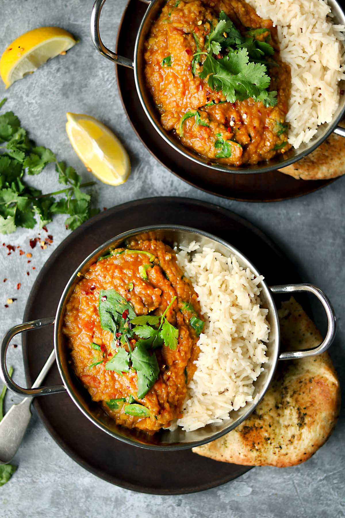 Dahl met rode linzen geserveerd op bloemkoolrijst, gegarneerd met verse koriander en citroen — koolhydraatarm dinnerrecept voor 2 porties