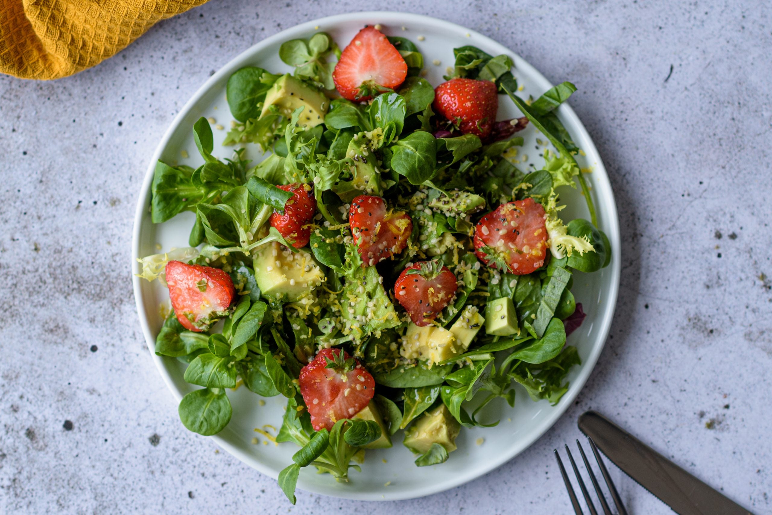 Hennepzaadsalade met avocado, aardbeien en spinazie op een bord met citroen dressing, zomerse styling