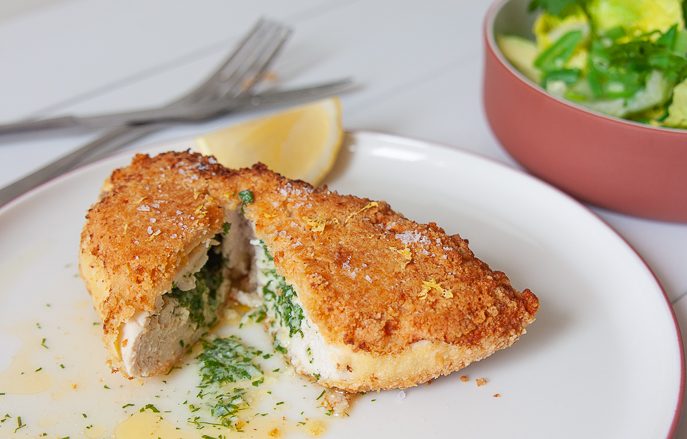 Keto kip kiev met amandelmeel korst op een bord met groene snijbonensalade en avocado