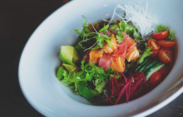 Sashimi salade met verse zalm, tonijn, avocado, komkommer en rode bietsla in een diep bord